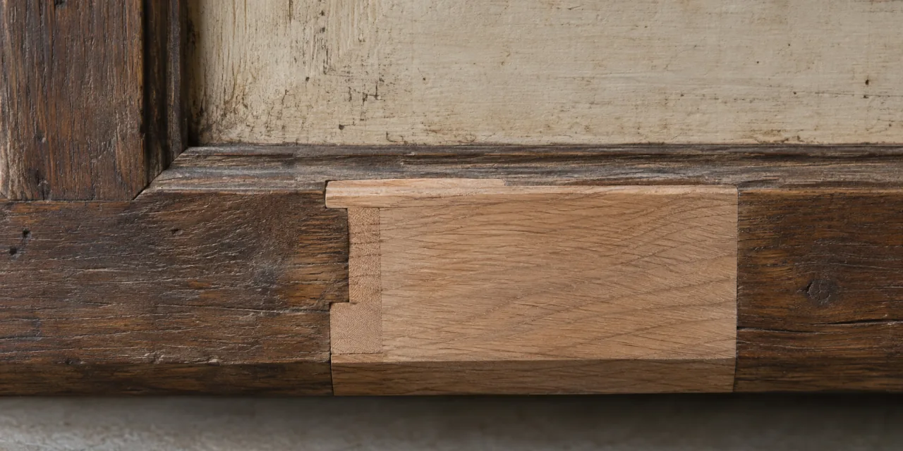 Reintegro di legno nuovo, più chiaro e riconoscibile, inserito nella traversa di un mobile antico